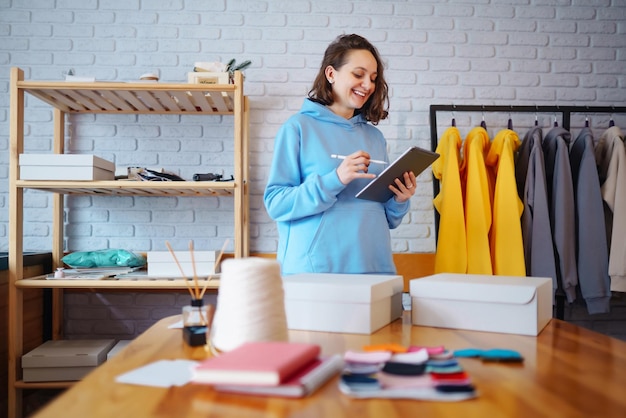 Vendeur entrepreneur propriétaire de petite entreprise à l'aide d'une tablette vérifiant les commandes de magasins de vêtements de commerce électronique