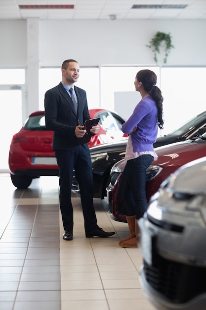 Vendeur et une femme qui parle à côté d&#39;une voiture