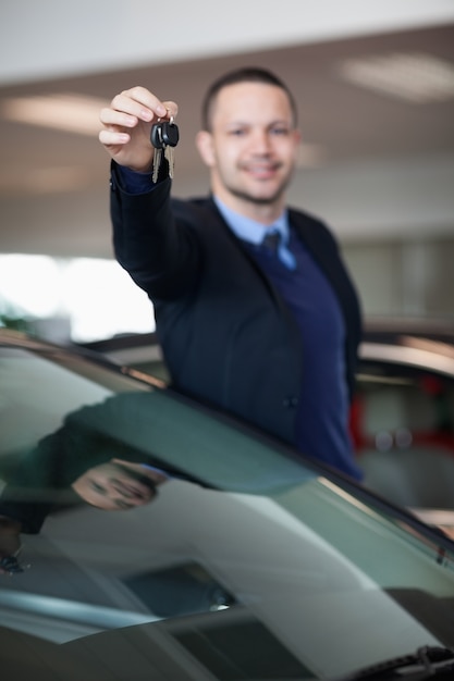 Vendeur levant le bras en tenant les clés de la voiture