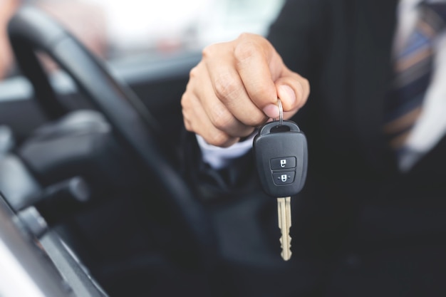 Le vendeur livre les nouvelles clés de voiture au client dans la salle d'exposition.