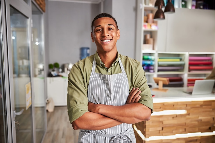 Photo vendeur de magasin de fleuriste avec un grand sourire sur son visage debout près d'une porte en verre