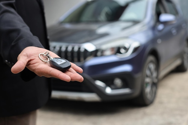 Vendeur méconnaissable offrant une clé de voiture vendant de l'automobile dans un magasin concessionnaire.