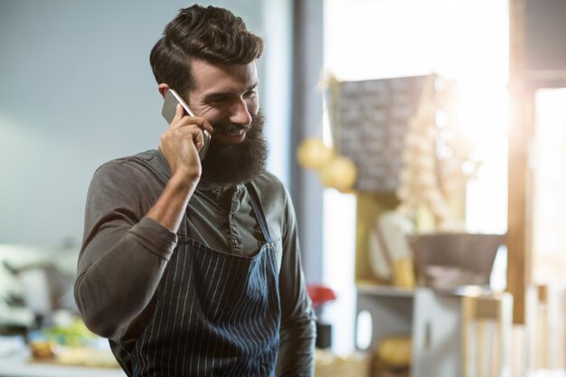 Vendeur parlant au téléphone mobile au comptoir