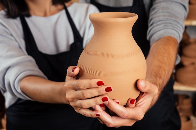 Un vendeur de poterie et vendeuse vend un pot de vase en argile en gros plan en atelier.