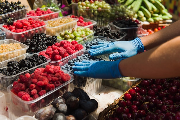 Vendeur préparant des baies fraîches biologiques au marché.