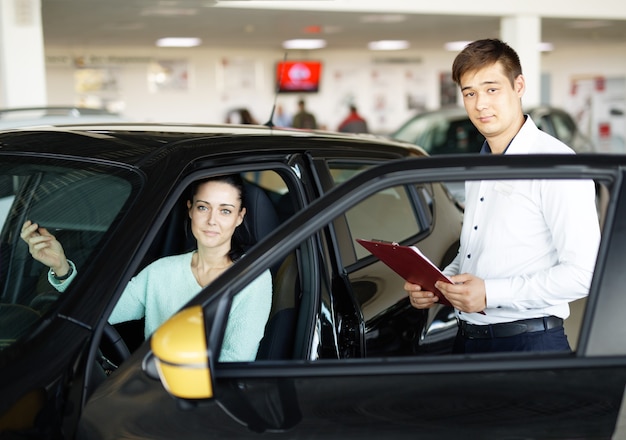 Vendeur présentant une nouvelle voiture aux clients auto shop