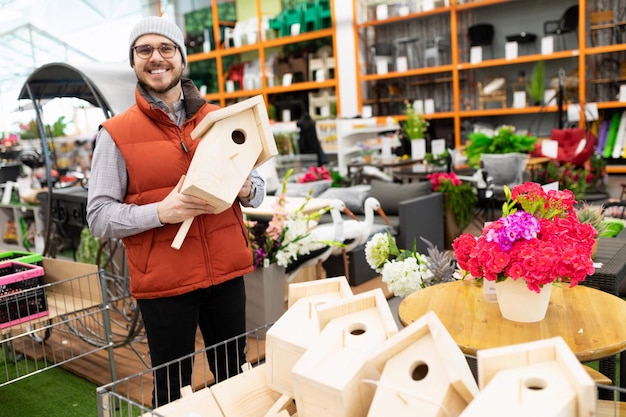 Le vendeur de produits faits à la main pour le jardin et le potager tient un nichoir dans ses mains