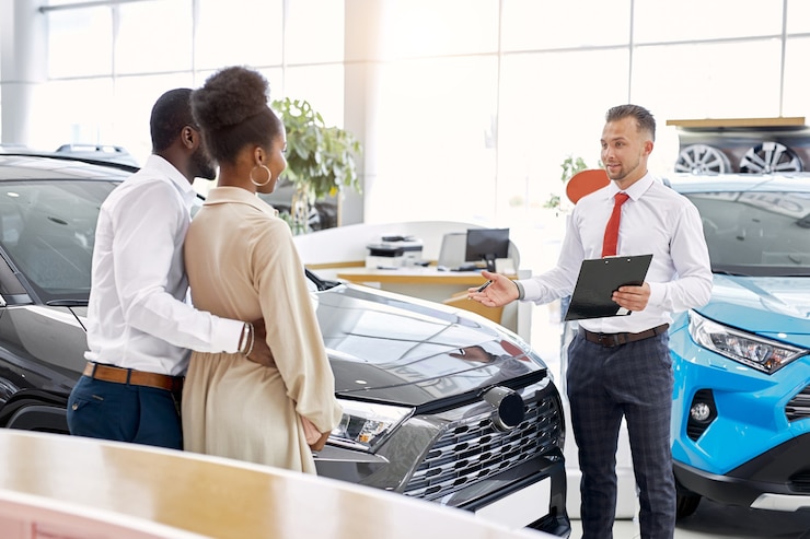 Photo vendeur sympathique et beau couple africain dans la salle d'exposition de voiture