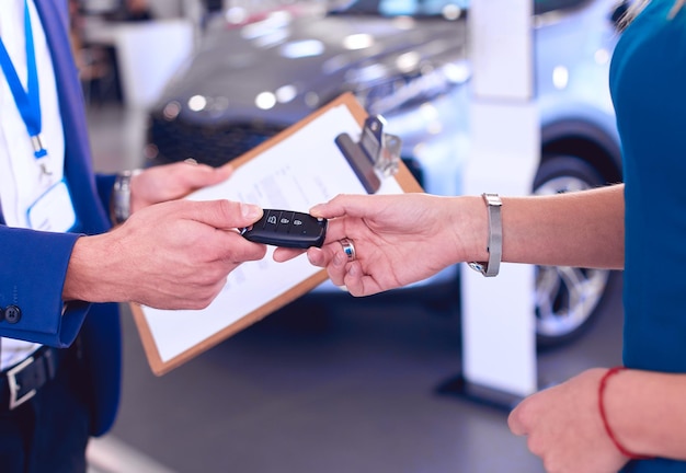 Un vendeur de voitures vend une voiture à un client heureux chez un concessionnaire automobile et remet les clés