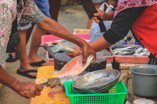 Photo des vendeurs préparant des poissons pour un client sur le marché des fruits de mer de kedonganan passer ikan jimbaran plage de bali