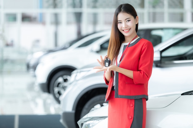 Vendeuse asiatique donnant la clé de la voiture sur le salon de l&#39;auto, entreprise automobile, vente de voiture.