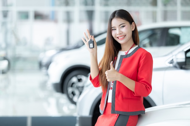 Vendeuse asiatique donnant la clé de la voiture sur le salon de l&#39;auto, entreprise automobile, vente de voiture.