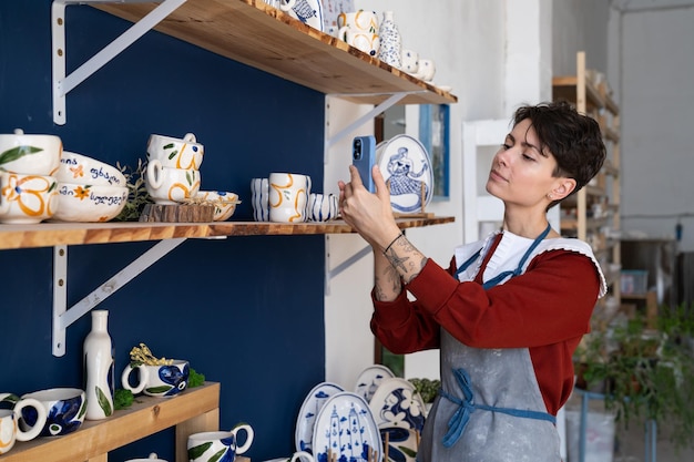 Une vendeuse caucasienne dans une boutique de souvenirs prend des photos de marchandises au téléphone pour les publier sur les réseaux sociaux