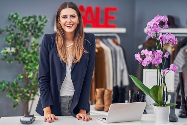 vendeuse dans sa boutique avec collection automne hiver