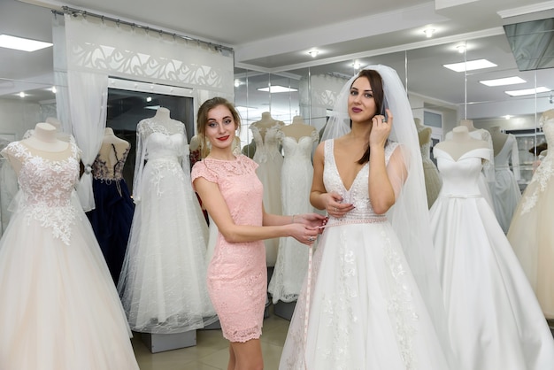 Vendeuse dans le salon de mariage aidant à la jeune mariée