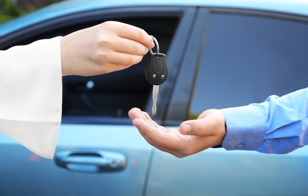 Vendeuse donnant la clé de voiture au client à l'extérieur