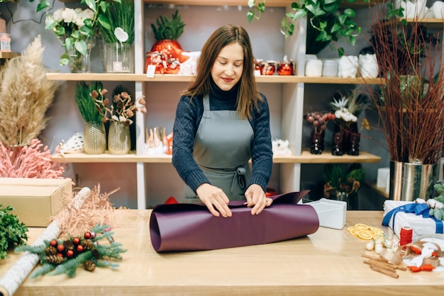 Une vendeuse enveloppe une boîte-cadeau dans du papier festif