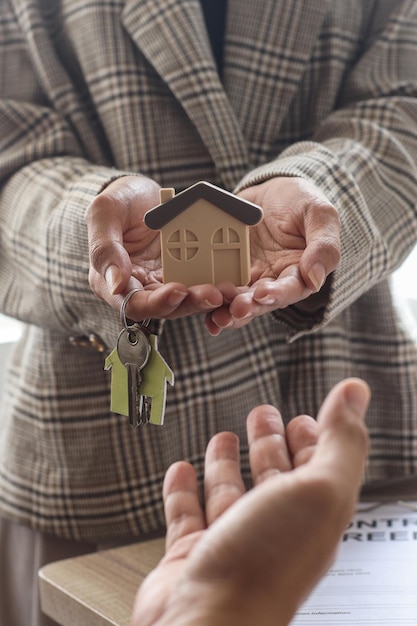 La vendeuse de maison livre un petit modèle de maison avec les clés de la maison à l'acheteur après les achats