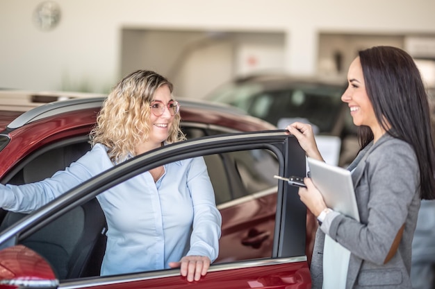 Une vendeuse de voitures et une cliente d'un concessionnaire automobile sont sur le point de conclure un accord de vente