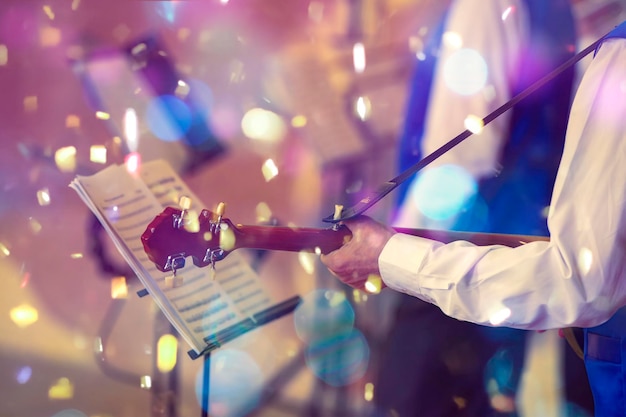 Événement musical Mains d'un musicien avec une guitare devant un nom en confettis lumineux