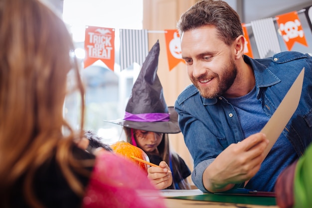 Venir aux enfants. Homme barbu portant une chemise en jean venant à ses enfants se préparant pour Halloween