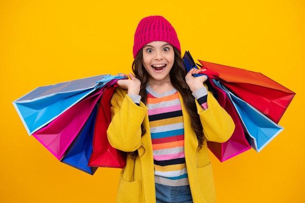 Vente d'achats d'hiver Belle mode adolescente enfant fille avec des sacs à provisions sur fond jaune