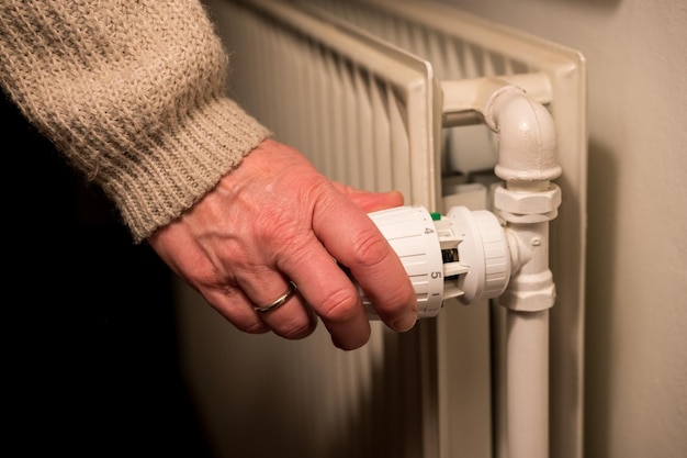 Photo vente thermostatique à main féminine sur le radiateur