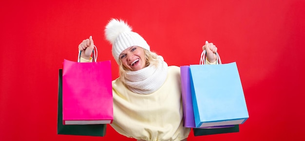 Ventes de vacances de bannière et portrait d'achats de femme gaie dans des vêtements d'hiver avec coloré