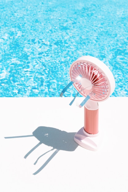 Ventilateur électrique rose à côté d'une piscine été et espace de copie de concept de voyage