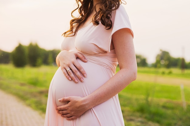 Ventre d&#39;une femme enceinte au coucher du soleil. Fille enceinte se sentir le bébé