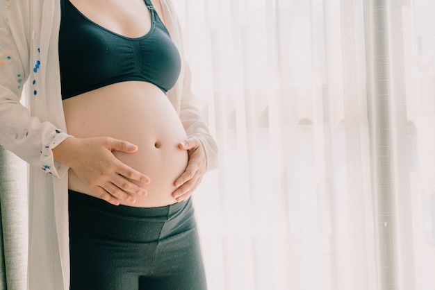 Ventre de femme enceinte avec les mains