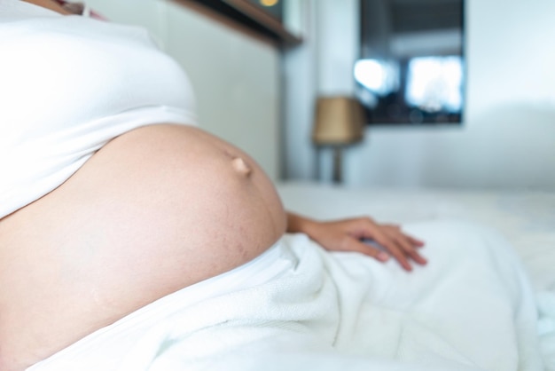 Ventre de femme enceinte se détendre sur le lit