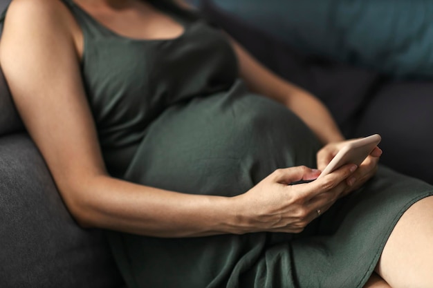 Le ventre de la femme enceinte et le téléphone en point de mire un moment de détente pour la femme enceinte