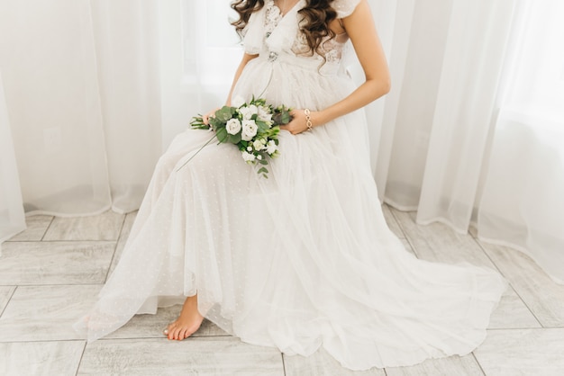 Ventre d'une fille enceinte dans une belle robe blanche