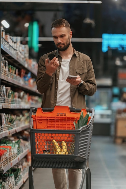 Vérifier les informations dans le téléphone L'homme fait ses courses au supermarché
