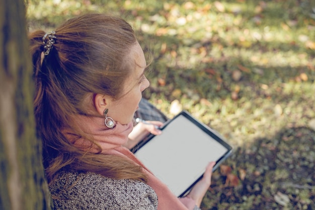 Véritable femme d'affaires avec ordinateur portable tablette au travail à l'extérieur dans le parc