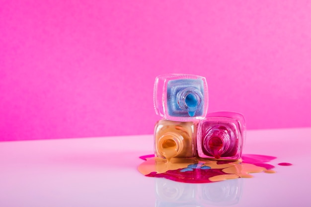 Photo vernis à ongles coloré renversé sur fond rose