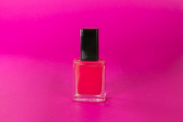 vernis à ongles rose chaud bouteille gros plan fond rose