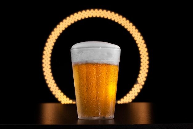 Photo verre américain avec de la bière froide sur un tableau noir et un anneau de lumière en arrière-plan