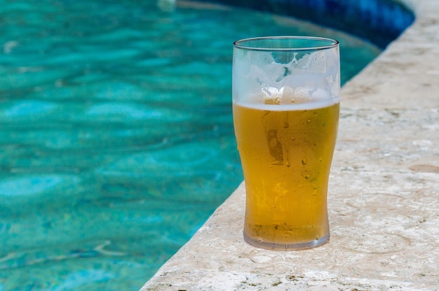 Verre de bière au bord de la piscine. Verre avec bière glacée. Boire de la bière au bord de la piscine