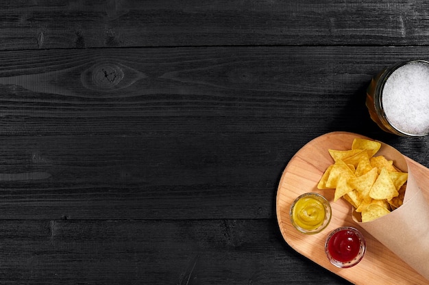 Verre de bière avec des chips de nachos sur un fond en bois