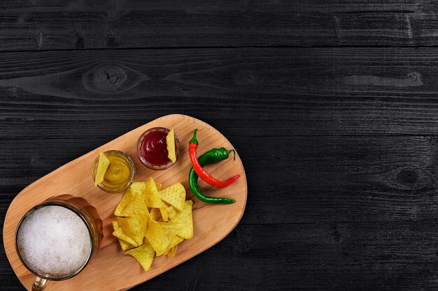 Verre de bière avec des chips de nachos sur un fond en bois