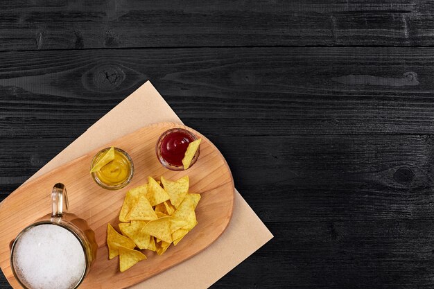 Verre de bière avec des chips de nachos sur un fond en bois