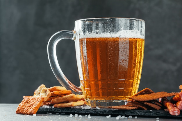 Verre à bière avec des collations de bretzel et de saucisses séchées se bouchent