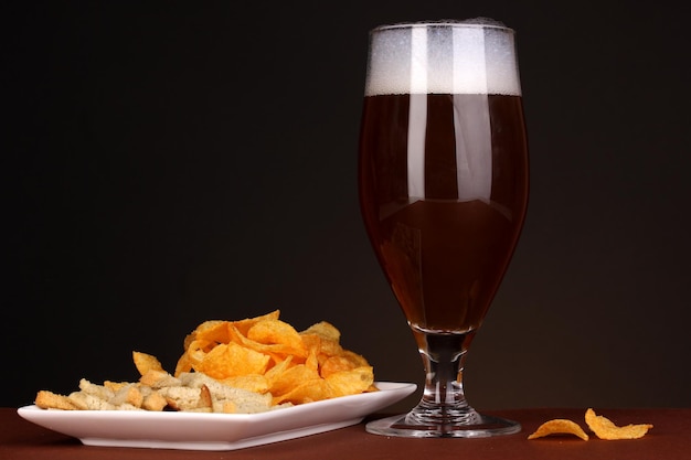 Verre de bière avec craquelins et frites sur fond marron