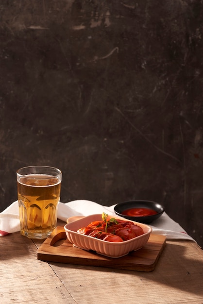 Verre de bière délicieuse avec des saucisses grillées sur table en bois