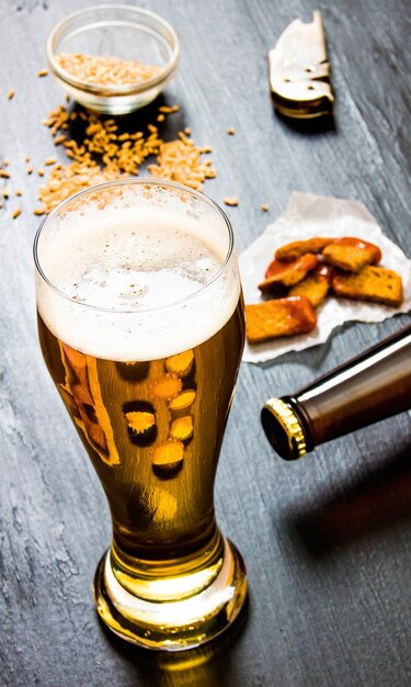 Verre de bière fraîche sur un fond en bois noir.