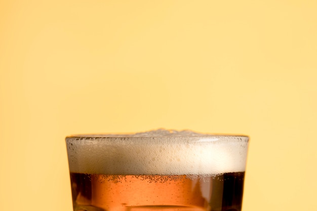 Photo verre de bière fraîche sur fond jaune