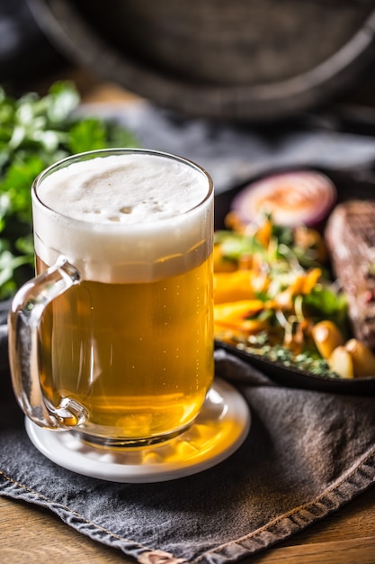 Photo verre de bière légère au pub ou au restaurant sur table avec de la nourriture délicieuse.