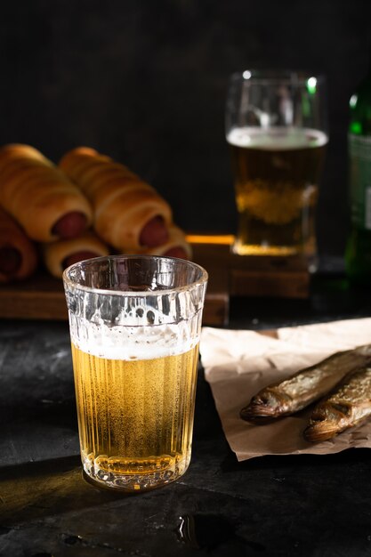 Un verre de bière légère et deux poissons séchés sur une table noire